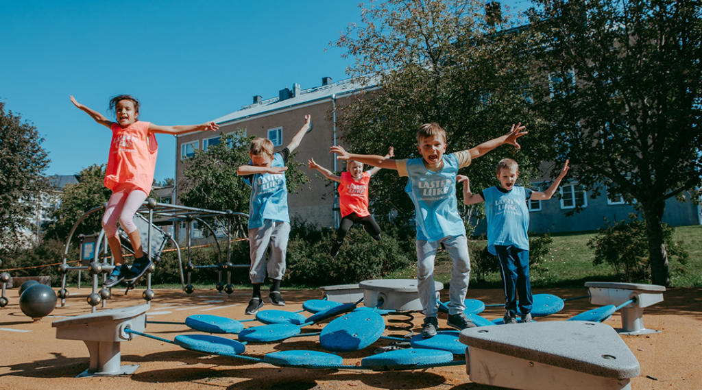 Kuvassa energisiä lapsia hyppii trampoliineilla