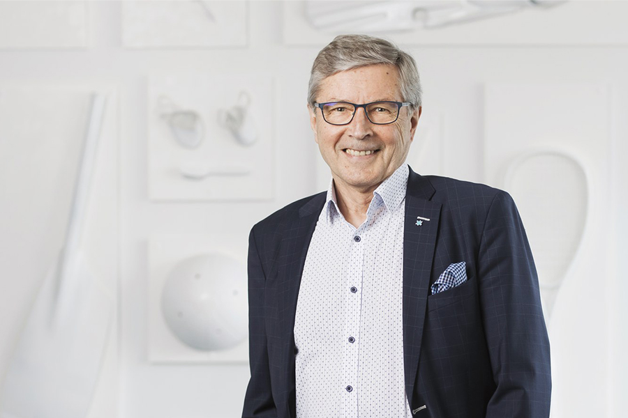 Olympiakomitean hallituksen jäsen Markku Haapasalmi hymyilee vaalean seinän edustalla.