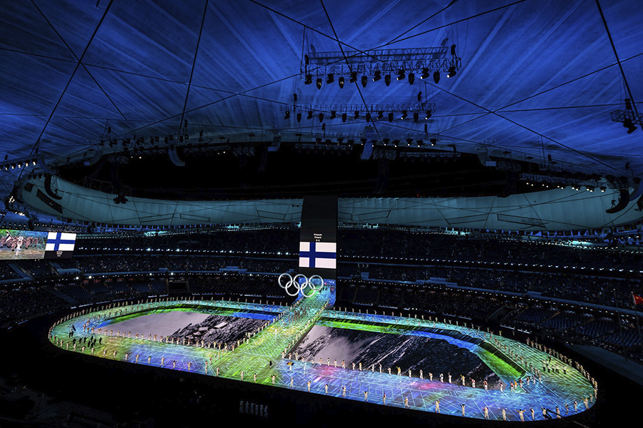Yläkulmasta otettu valokuva Pekingin olympiastadionilta olympialaisten avajaisista. Stadion on valaistu sinisin valoin ja screeneillä on Suomen lippu.