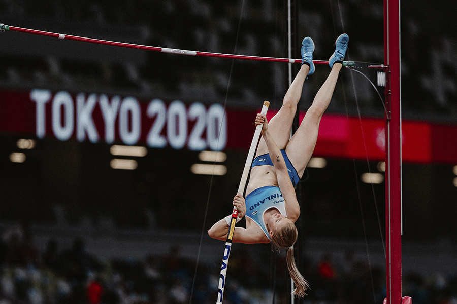 Seiväshyppääjä Wilma Murto on taivuttamassa hyppyänsä riman yli Tokion olympialaisissa. Taustalla yleisurheilustadionin katsomo.