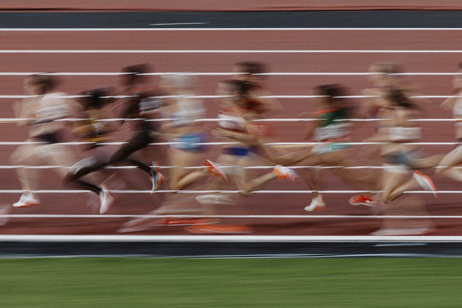 Kuvassa juoksuradalla juoksevia urheilijoita. Urheilijat ovat kuvassa sumeita ja epätarkkoja.
