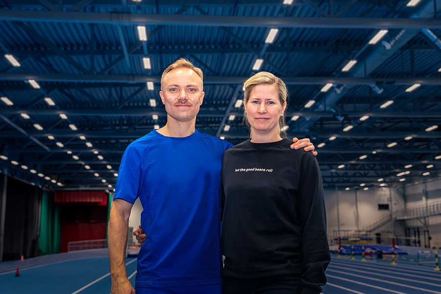 Kuvassa ovat juoksija Joonas Rinne ja Härkiksen brändipäällikkö Anna-Maria Kinnunen. He seisovat kuvan etualalla. Takana urheiluhalli.